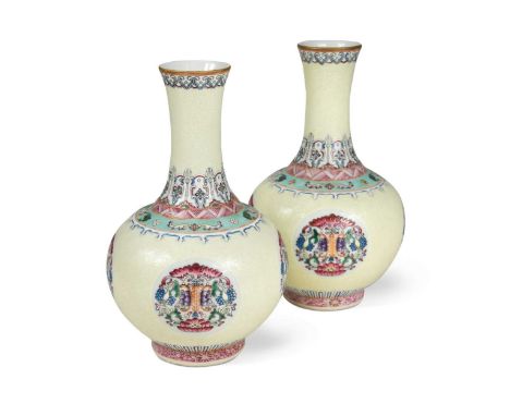 A pair of Chinese pale yellow ground bottle vases,  enamelled with four circular shou and bat motifs, bearing Qianlong seal m