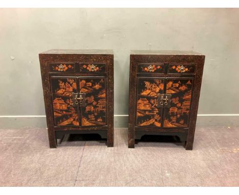 A pair of black lacquered bedside cabinets decorated with pagodas in a landscape, each with two drawers over two cupboard doo