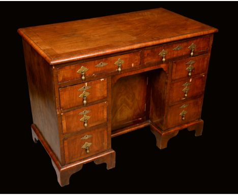A Queen Anne style walnut kneehole desk, crossbanded top with matched veneers above a pair of frieze drawers, cupboard to nic