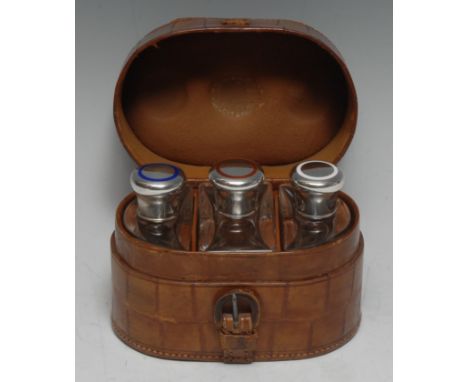 A George V silver and enamel mounted travelling cologne set, the crocodile skin case enclosing three scent bottles, each scre