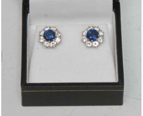 A pair of sapphire and diamond cluster earrings, each with a central vibrant light blue round cut sapphire approx 0.60ct, sur