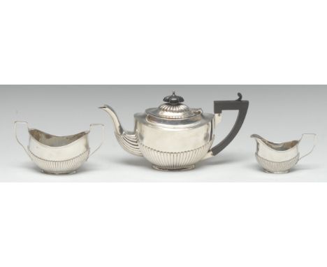 An Edwardian silver three piece half-fluted oval bachelor's tea service, comprising teapot, milk jug and sugar basin, angular