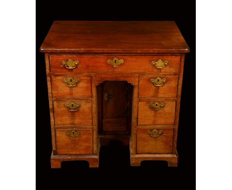 A George III mahogany kneehole desk, rounded rectangular top above a frieze drawer, cupboard to niche, flanked by two rows of