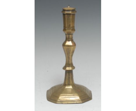 An early 18th century French brass candlestick, panelled sconce, knopped stem, stepped canted square base, 21cm high, c.1710