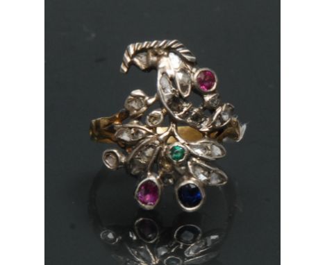 A multi gem diamond, emerald, sapphire and ruby floral finger ring, open floral crest inset with twenty one mixed cut diamond