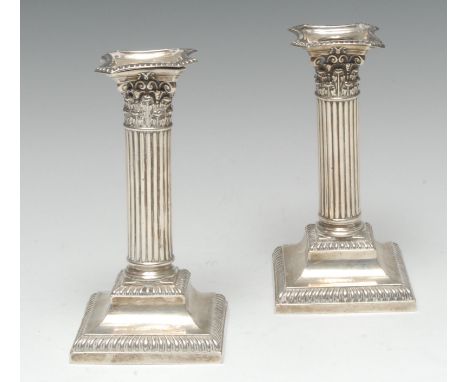 A pair of George V silver fluted Corinthian column candlesticks, detachable nozzles, spreading square bases, gadrooned border