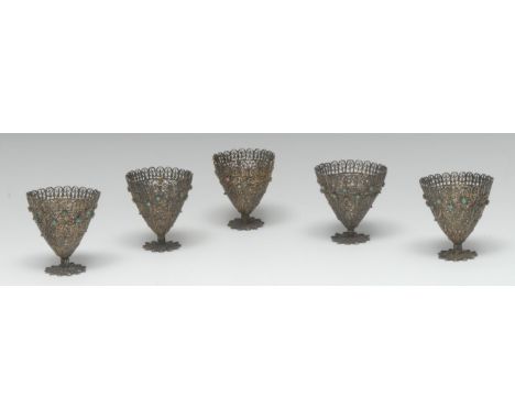 A set of five silver coloured metal filigree zarfs, each applied with turquoise cabochons, 6cm high, 19th century