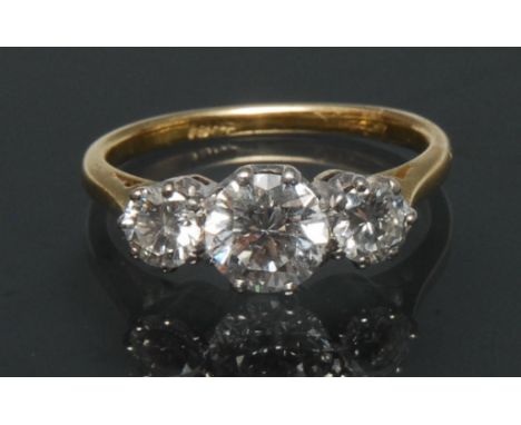 A diamond trilogy ring, central old brilliant cut diamond approx 1.03ct, flanked by a smaller conforming diamond either side,