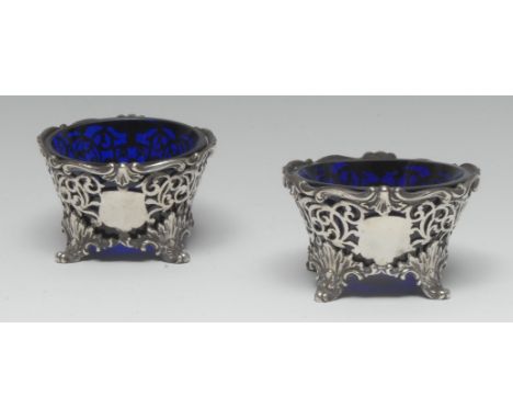 A pair of William IV Rococo Revival silver shaped circular salts, pierced borders, acanthus feet, blue glass liners, 8.5cm di