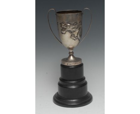 A Chinese silver presentation cup, repousse chased with a ferocious dragon, scroll handles, domed circular foot, 18cm high, W