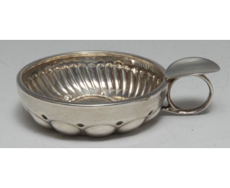 A 19th century French silver wine taster, the circular bowl fluted and embossed with domed reserves, ring handle with thumb-r