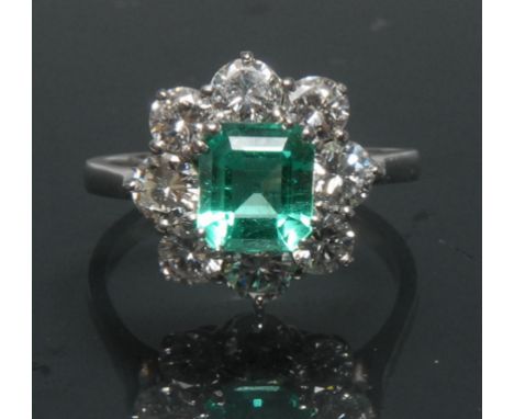 A Columbian emerald and diamond cluster ring, central rectangular cut vibrant green transparent certified emerald, measuring 