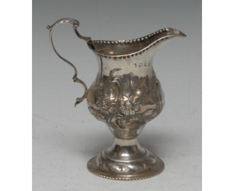 A George III silver pedestal cream jug, embossed and engraved with foliate scrolls, vacant cartouche, Thomas Shepherd, London