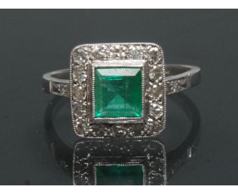 An emerald and diamond ring, central square table cut emerald approx 0.85ct, surrounded by a collar of sixteen round brillian