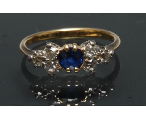 A early 20th century sapphire and diamond cluster ring, central oval deep blue sapphire, approx 0.18ct, flanked either side b