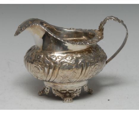 A George IV silver cream jug, embossed with foliate scrolls, resting on four claw feet, 10cm high, Jonathan Hayne, London 182