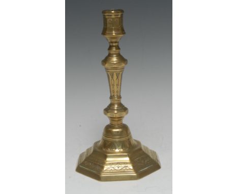 An early 18th century French brass octagonal candlestick, chased with swags, bell-husks and diapers, knopped stem, stepped ba