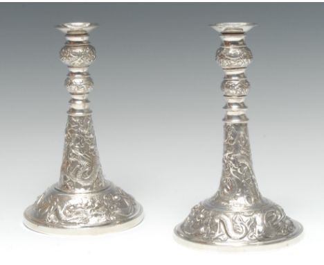A near pair of Chinese silver candlesticks, each chased with ferocious dragons chasing flaming pearls, detachable nozzles, Wa