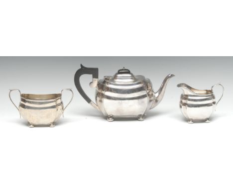 A George V silver three piece boat shaped tea service, comprising rectangular teapot, milk jug and sugar basin, scroll-capped