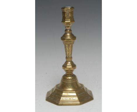 An early 18th century French brass octagonal candlestick, chased and wrigglework engraved with flowerheads and meandering mot