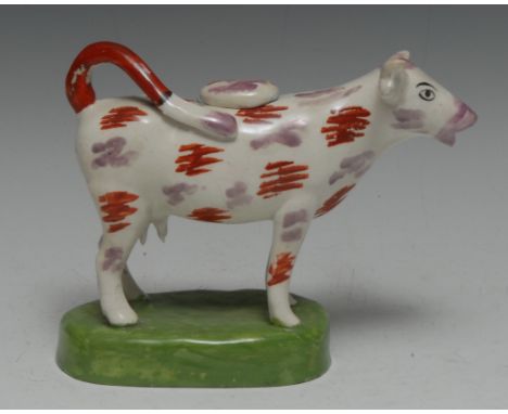 A 19th century Swansea type cow creamer, purple lustre and iron red patches, oval green base, 18.5cm wide, 14cm high Conditio