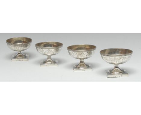 A set of four George III silver circular pedestal salts, each reeded rim above a bright-cut engraved band of flowers and scro
