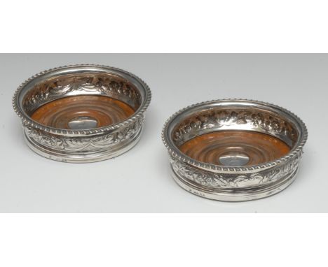 A pair of George IV silver bowed circular wine coasters, each with gadrooned border above a chased band of flowers and stiff 