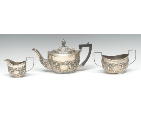 A Victorian silver boat shaped bachelors three piece tea service, each embossed with acanthus leaves and scrolls, angular ebo