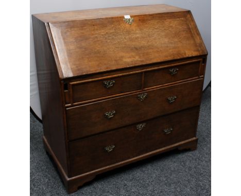 A George III oak bureau, fall front enclosing pigeon holes and small drawers, above two short and two long graduated drawers,