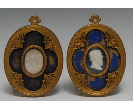 A pair of Neo-Gothic design ormolu oval frames, enclosing 19th century embossed and cut paper Grand Tour 'cameo' portrait pro