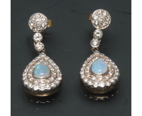 A pair of opal and diamond drop earring, each with a central opal pear cabochon, surrounded by a double band of thirty six pa