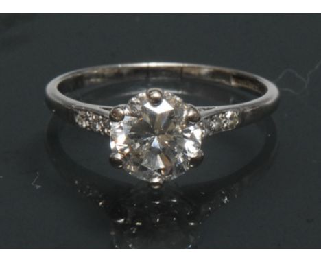 A diamond solitaire ring, round brilliant cut approx 1.59ct, six claw set crest, above trilogy diamond inset shoulders, Plati