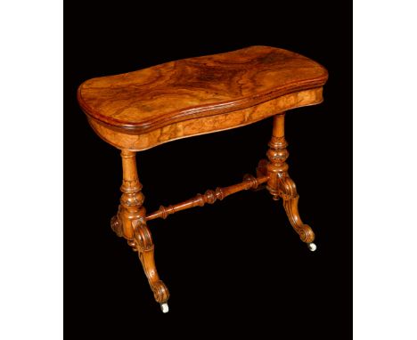 A Victorian walnut shaped rectangular card table, folding top with matched veneers enclosing an inset baize lined playing sur