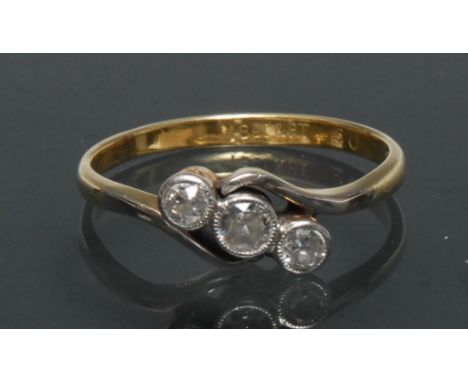 A diamond trilogy twist ring, central old brilliant cut diamond approx 0.12ct, flanked by a graduated conforming diamond eith