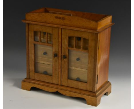 A Secessionist oak table cabinet, the architectural pediment inlaid with three copper lozenges, above a pair of glazed doors 