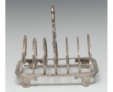 A George IV silver seven-bar toast rack, lotus-grasped loop handle, arched double-scroll divisions, anthemion scroll feet, 16