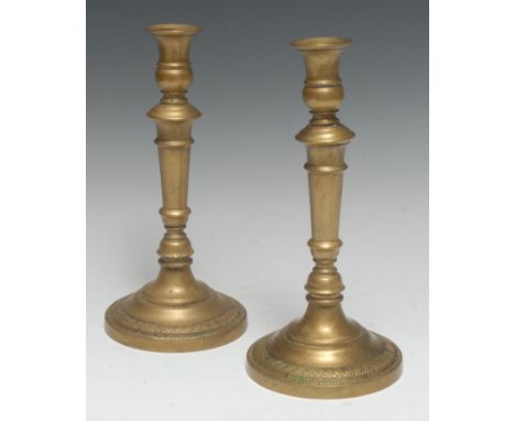 A pair of French Empire brass candlesticks, campana sconces, knopped stems, circular bases with engine turned borders, 26.5cm