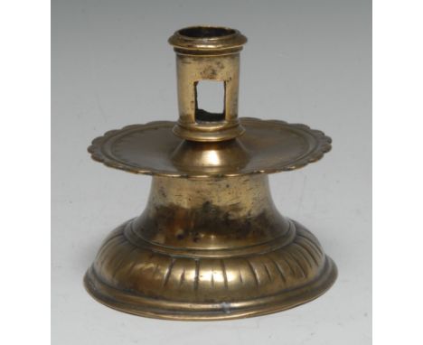 A 16th century brass capstan candlestick, pierced cylindrical sconce, broad shaped circular drip pan with a band of punched f