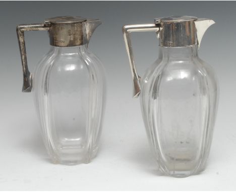 A pair of Edwardian silver mounted clear glass claret jugs, hinged covers, angular handles, 22cm high, John Grinsell &amp; So