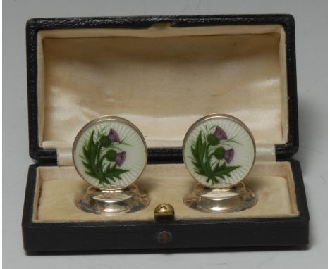 A pair of George V silver and enamel menu holders, decorated in polychrome with Scottish thistles, circular bases, 3.5cm high
