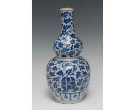 A Chinese porcelain double-gourd vase, painted in underglaze blue with a peonies and leafy scrolls, the base with a frieze of