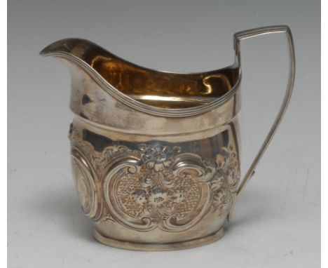 A George III silver boat shaped cream jug, later chased with flowers and C-scrolls, angular scroll handle, gilt interior, 11c