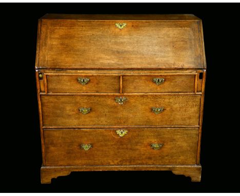 An early George III oak bureau, fall front with reading ledge, enclosing an architectural interior with panel door flanked by