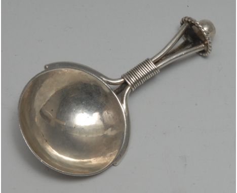 An Arts and Crafts silver caddy spoon, circular planished bowl, the stylised bound tripartite stem with scroll rat tail, ball