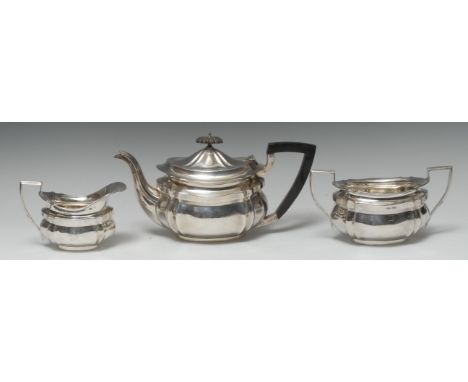 A George V silver three piece shaped oval tea service, comprising teapot, milk jug and sugar basin, fluted angles, the teapot