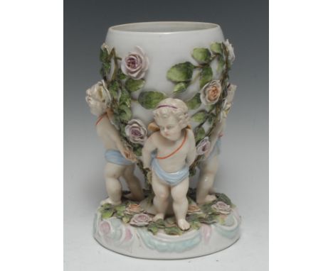 A late 19th century Continental porcelain vase, the ovoid body encrusted with roses and foliage, supported by three scantily 