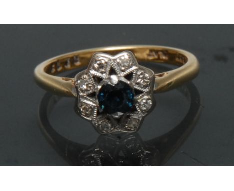 A diamond and blue stone cluster ring, possibly blue spinel, central claw set above a surrounding band of eight brilliant and