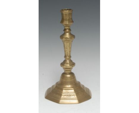 An early 18th century French brass octagonal candlestick, chased with flowers, stiff leaves and lozenges, knopped stem, stepp