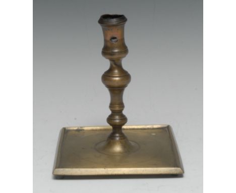 A 17th century French brass candlestick, waisted sconce, knopped stem, broad square base, stump feet, 16.5cm high, c.1660
