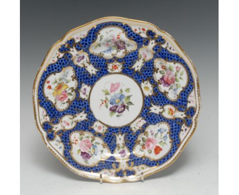 A rare Derby shaped circular plate, painted in Worcester style with fan and vase shaped reserves, with flowers on a scale blu